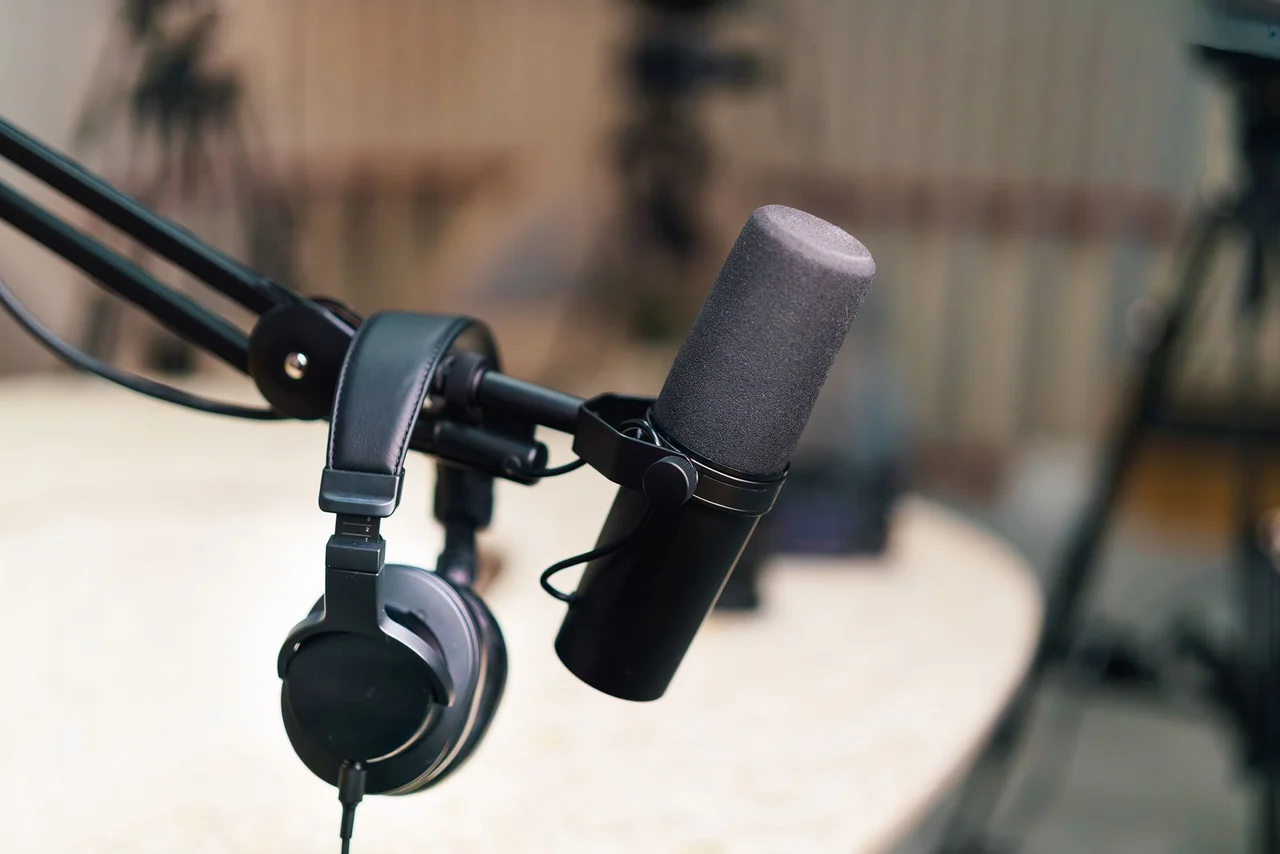 A microphone on a boom arm and headphones in a real podcast recording studio